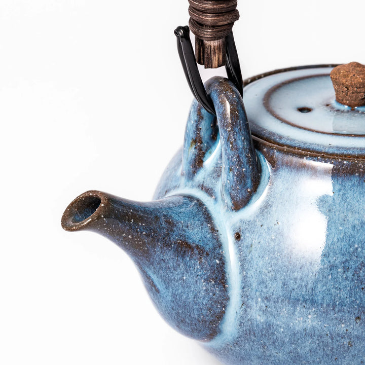 Terracotta blue ceramic teapot with rustic brown rim and woven metal handle, handcrafted in Japan for serving green tea or everyday brewing.