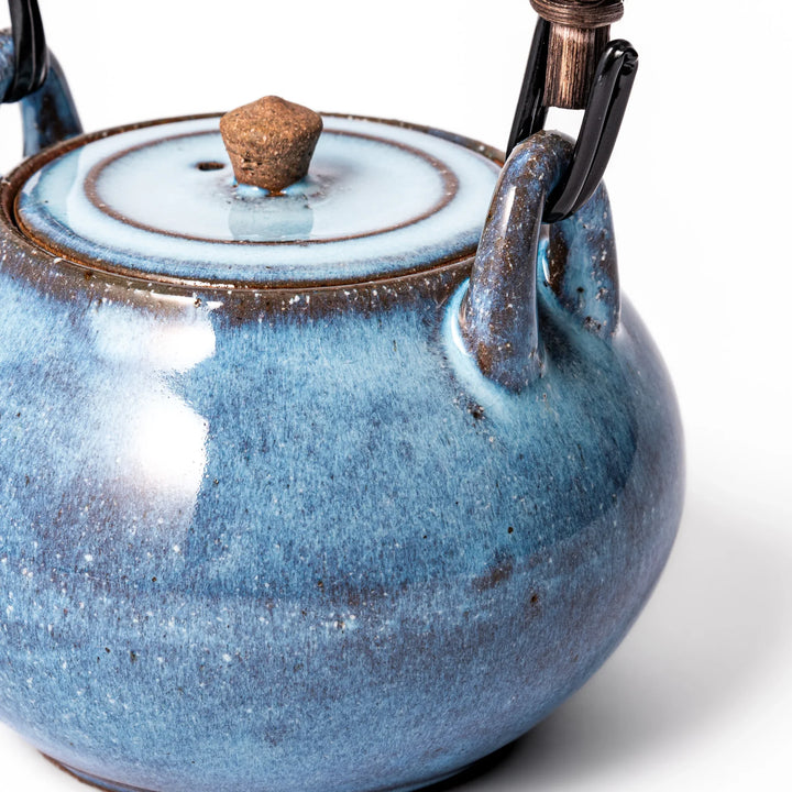Terracotta blue ceramic teapot with rustic brown rim and woven metal handle, handcrafted in Japan for serving green tea or everyday brewing.