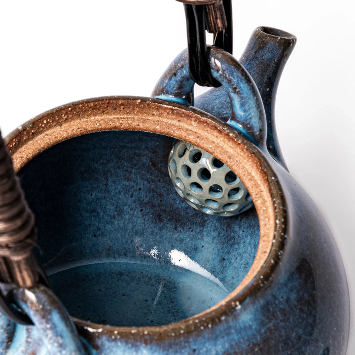 Terracotta blue ceramic teapot with rustic brown rim and woven metal handle, handcrafted in Japan for serving green tea or everyday brewing.