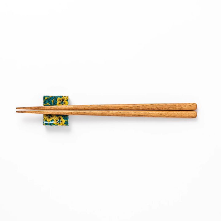 Rectangular Japanese ceramic chopstick rest decorated with vivid yellow floral design and teal leaves, bringing elegance and color to your dining table.