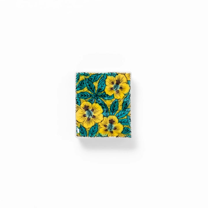 Rectangular Japanese ceramic chopstick rest decorated with vivid yellow floral design and teal leaves, bringing elegance and color to your dining table.