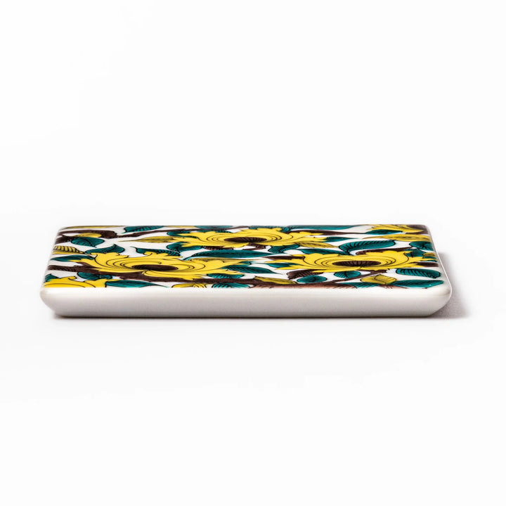 Square Japanese ceramic coaster adorned with vivid yellow peony blooms and teal leaves, adding elegance and charm to any dining table setting.