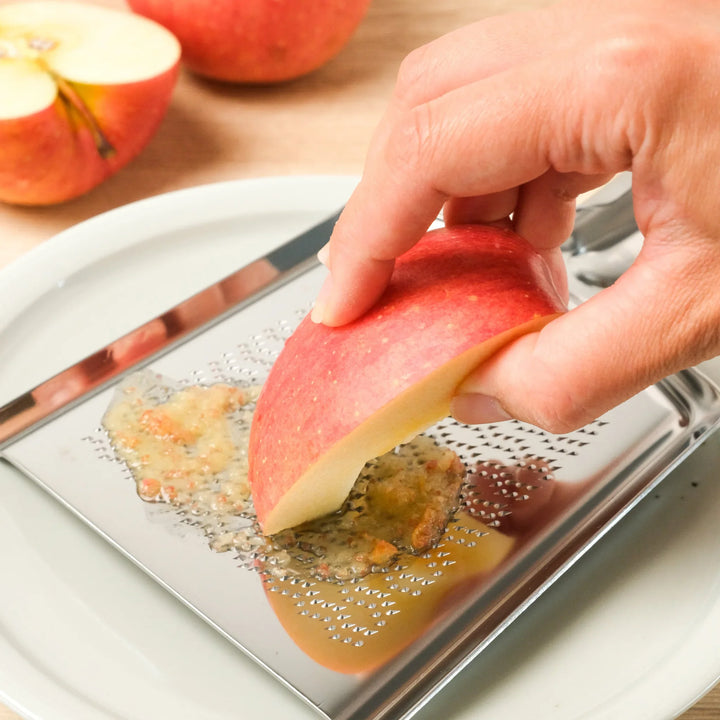 Grating an apple on a Shark Skin Stainless Steel Wasabi Grater, ideal for wasabi, ginger, and fruit with fine, even texture.