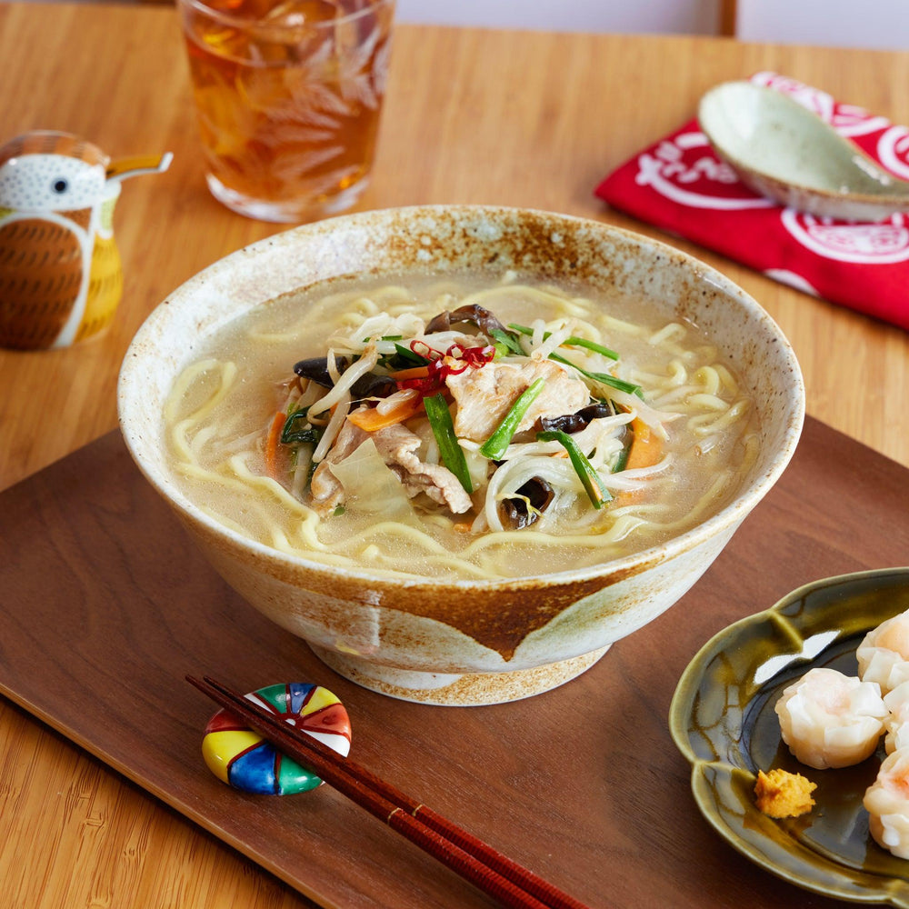 Handcrafted ramen bowl with earthy brown and beige tones, filled with vegetable ramen and placed on a wooden serving tray.