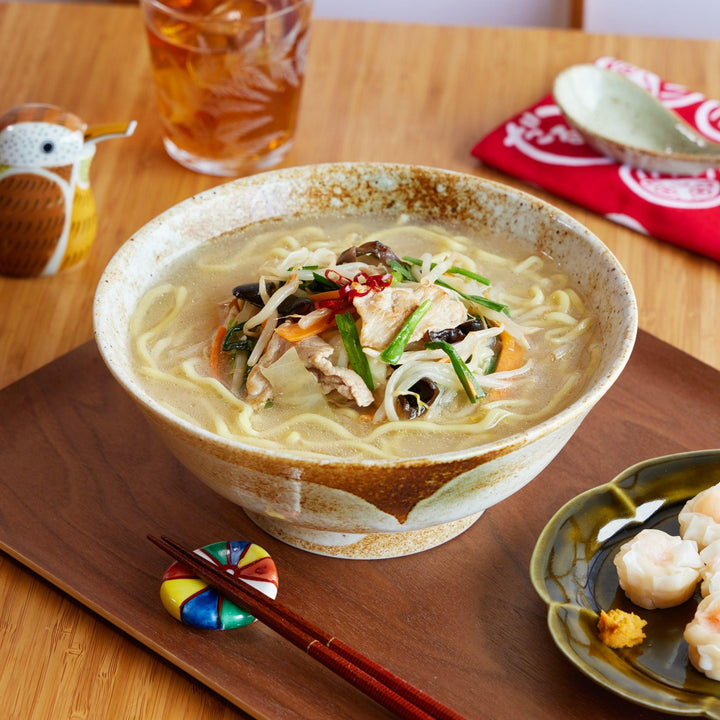 Handcrafted ramen bowl with earthy brown and beige tones, filled with vegetable ramen and placed on a wooden serving tray.