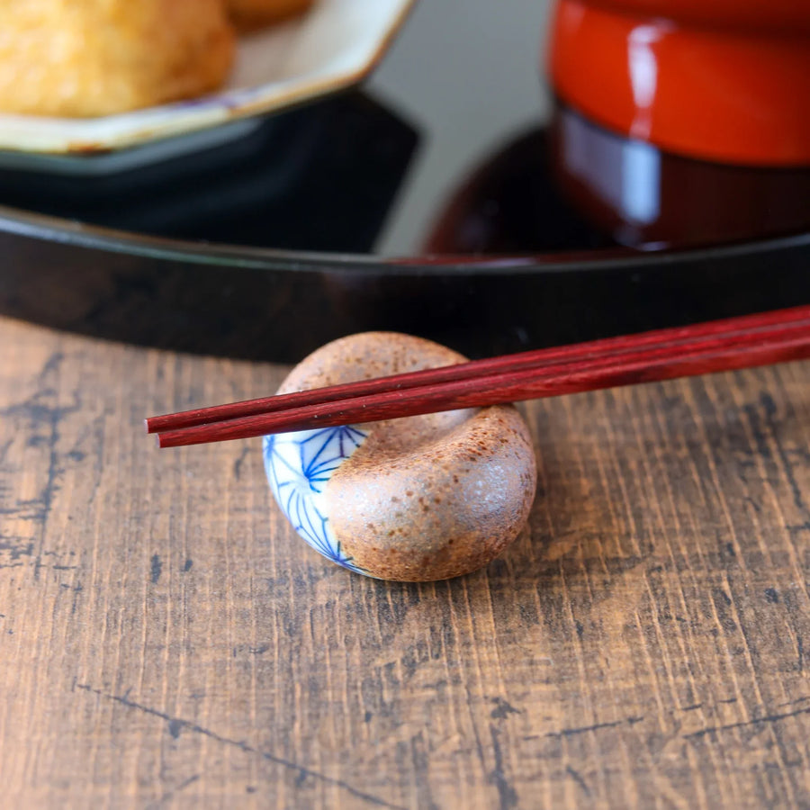 A round ceramic Japanese chopstick rest with a half-glazed hemp leaf pattern and rustic texture.
