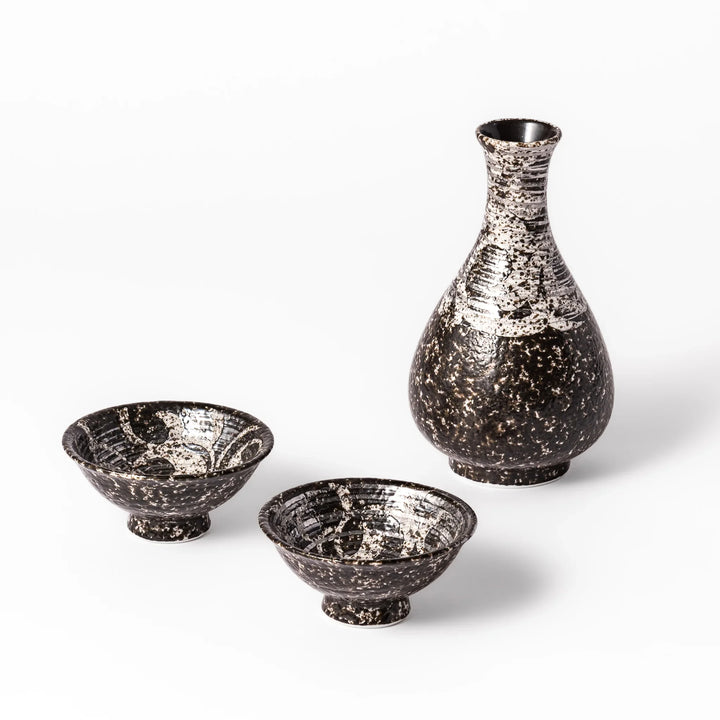 Dark brown and silver ceramic sake flask with two footed cups featuring a rustic speckled glaze and traditional handcrafted look.