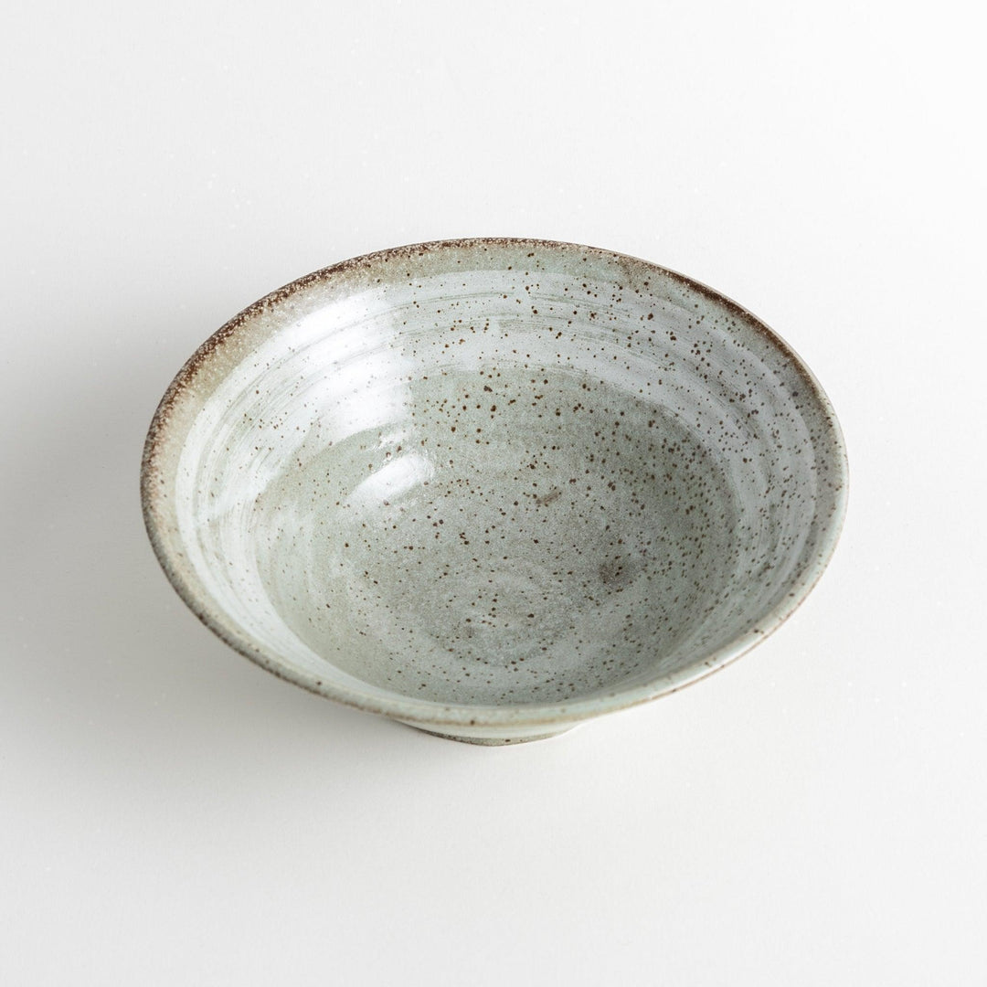 A light gray, wide-rimmed bowl with a textured and speckled surface.