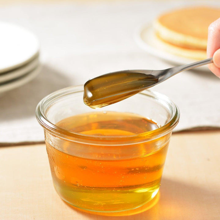 Long-handled stainless steel honey spoon with a uniquely shaped flat scoop