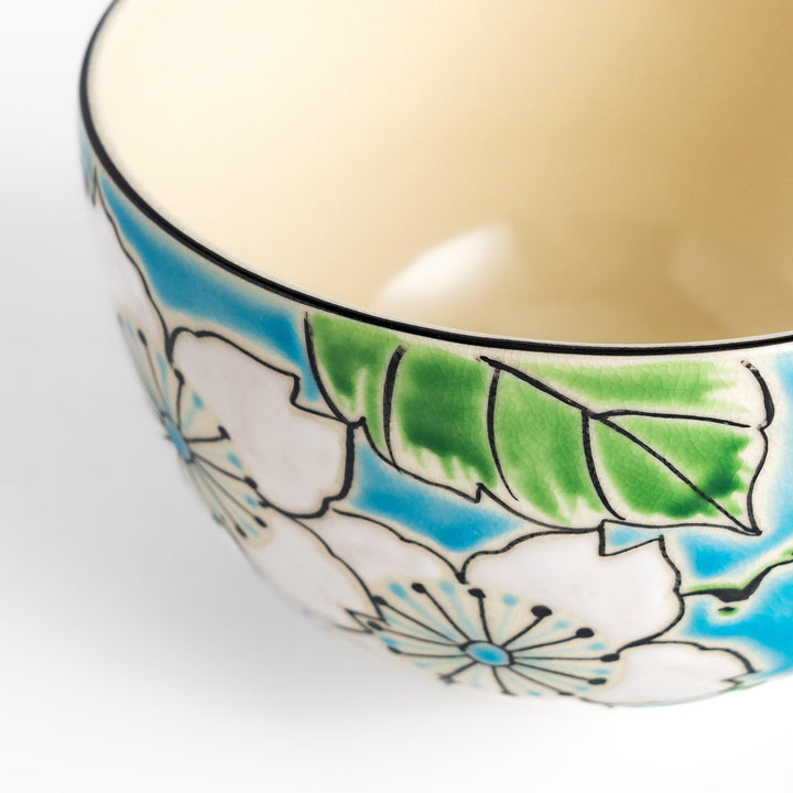 Eye-catching Matcha bowl showcasing a beautiful floral pattern in white and green against a bright blue backdrop, ideal for preparing and serving Matcha.