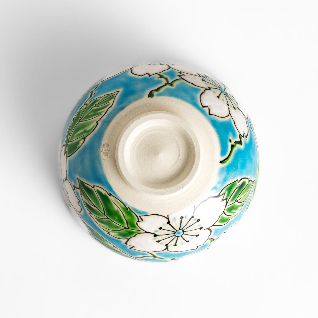 Eye-catching Matcha bowl showcasing a beautiful floral pattern in white and green against a bright blue backdrop, ideal for preparing and serving Matcha.