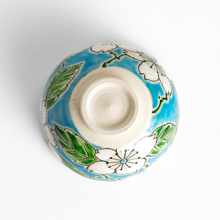 Eye-catching Matcha bowl showcasing a beautiful floral pattern in white and green against a bright blue backdrop, ideal for preparing and serving Matcha.