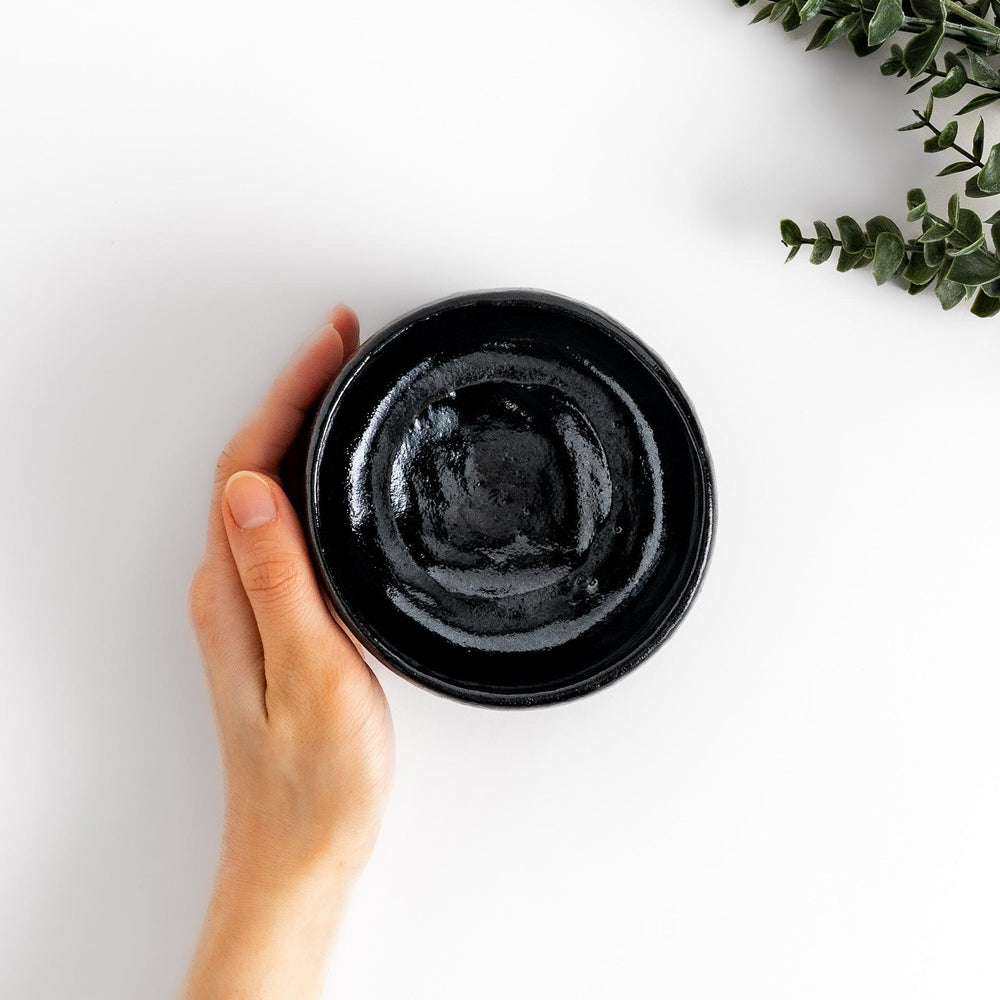 Unique black Raku ware Matcha bowl, handcrafted with traditional Japanese techniques, featuring a rustic texture and a wabi-sabi aesthetic.