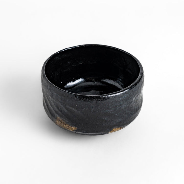 Unique black Raku ware Matcha bowl, handcrafted with traditional Japanese techniques, featuring a rustic texture and a wabi-sabi aesthetic.