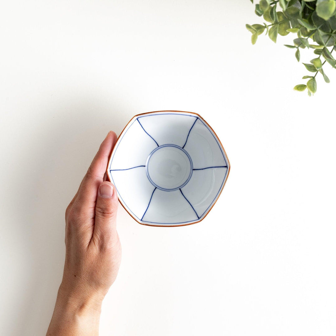 A white ceramic bowl with a flared, scalloped edge and simple blue line detailing.
