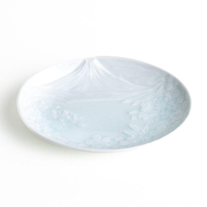 A round celadon dessert plate with a subtle raised pattern depicting Mount Fuji and surrounding nature, with a smooth, glossy finish.