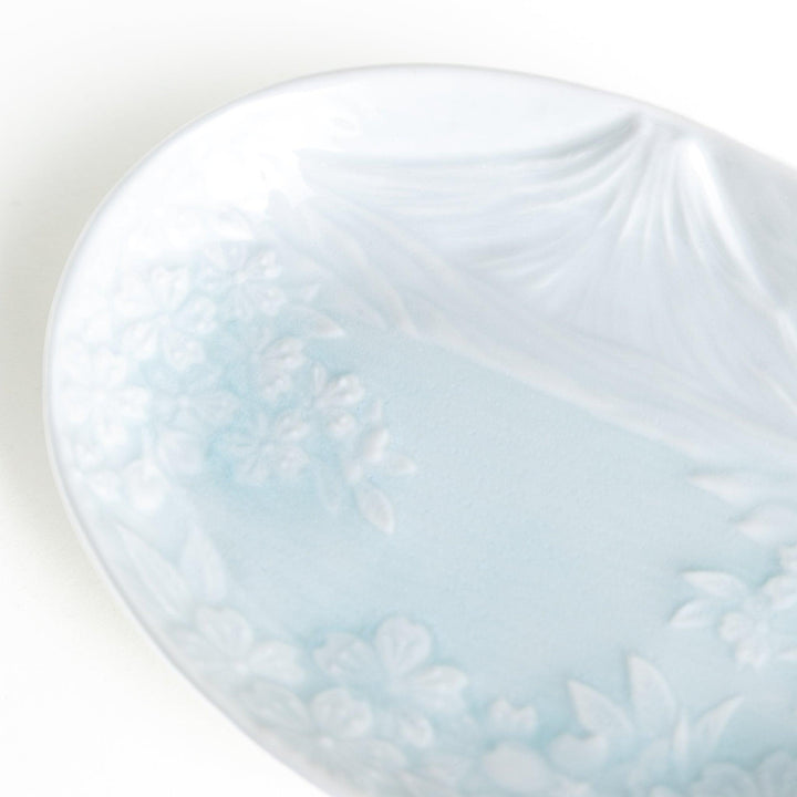 A round celadon dessert plate with a subtle raised pattern depicting Mount Fuji and surrounding nature, with a smooth, glossy finish.