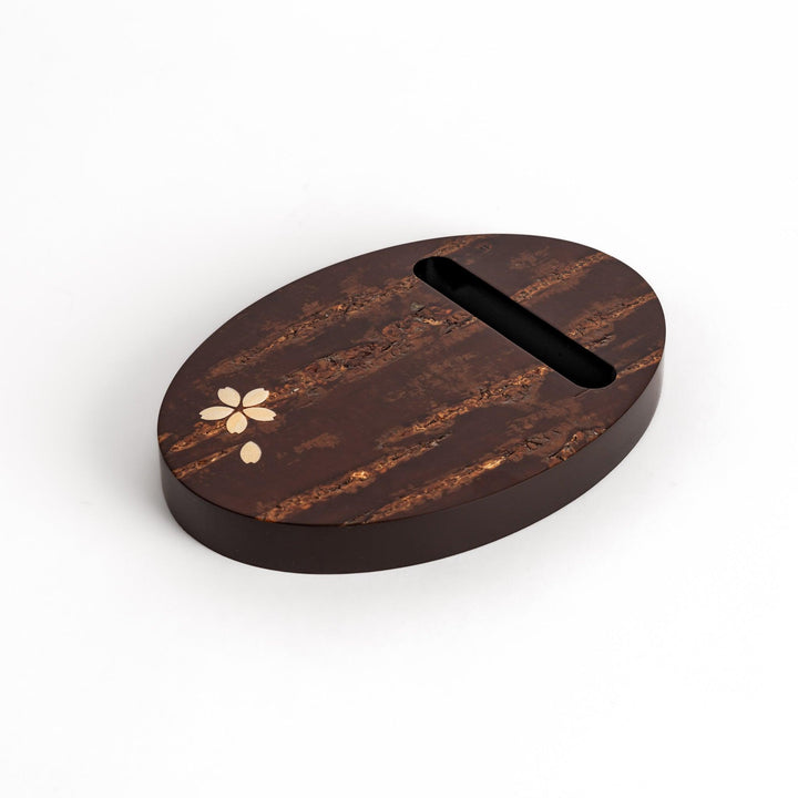 Oval-shaped cherry bark teapot rest with a beautiful natural grain and a delicate cherry blossom inlay, adding a touch of elegance to your tea time.