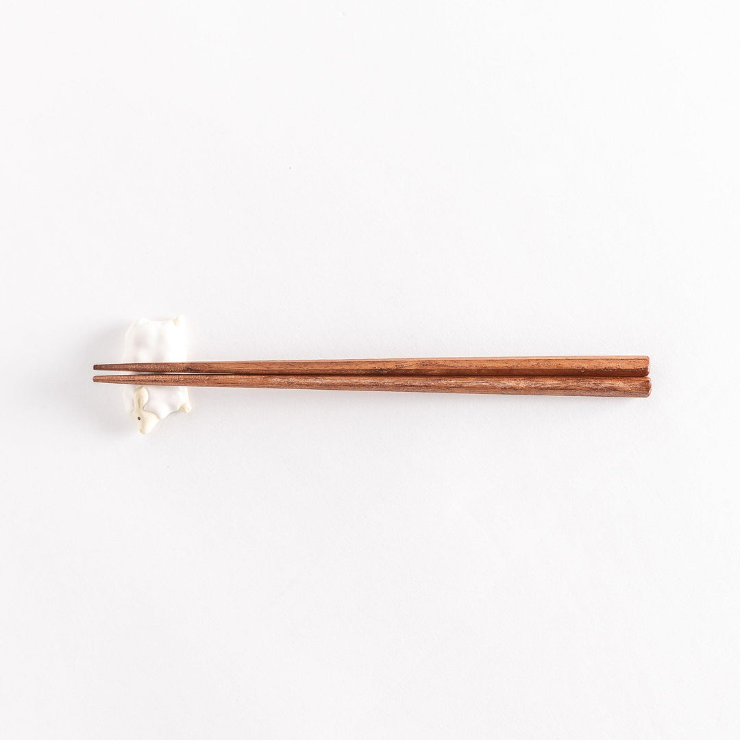 Full view of the sheep chopsticks rest with chopsticks resting across its soft, rounded body.