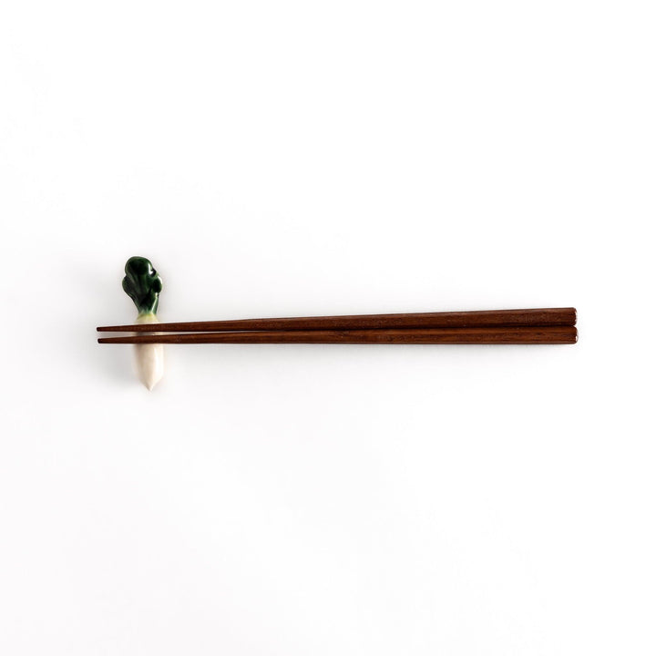 Wooden chopsticks resting on the daikon radish-shaped ceramic chopstick rest, highlighting its elegant and functional design.