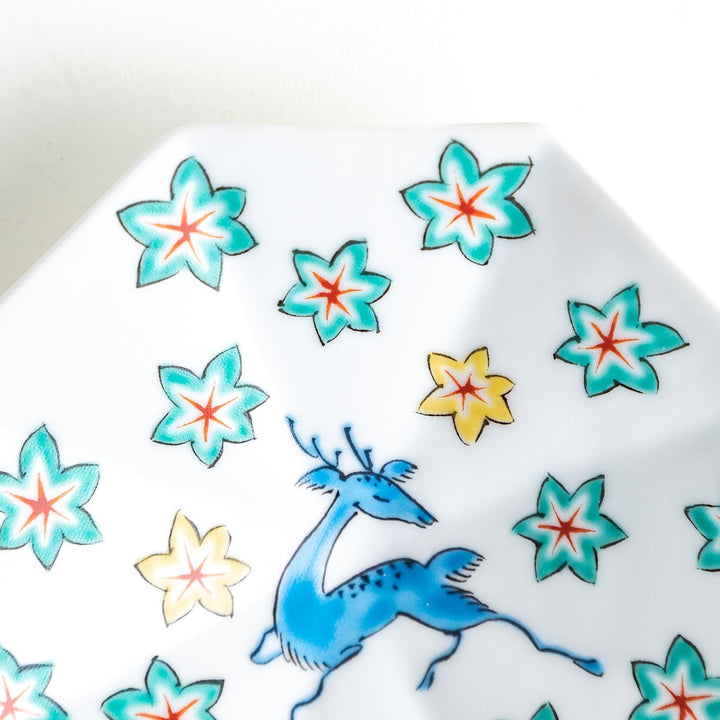 Octagonal plate with a blue deer surrounded by red and green floral patterns.