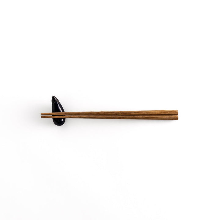 Wooden chopsticks resting on the glossy purple ceramic eggplant chopstick rest, showcasing its balance and charm.