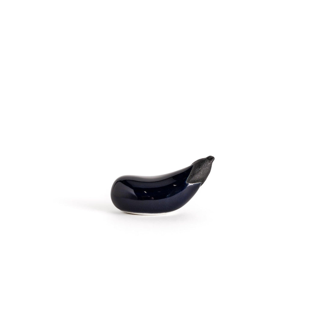 Glossy ceramic eggplant chopstick rest in deep purple with a textured black stem, perfect for adding a unique touch to your dining setting.