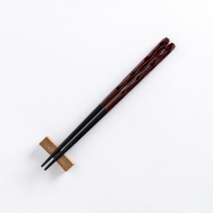 Ember color chopstick resting on a chopstick rest, highlighting its warm, rich hue and intricate design.