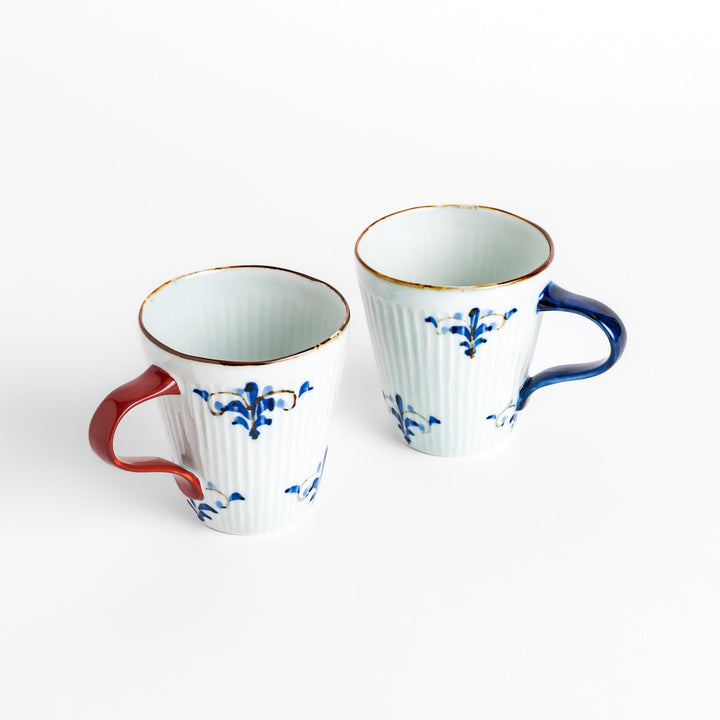 Two floral leaves mugs featuring blue and red handles, decorated with blue floral patterns and golden accents for a stylish, timeless design.