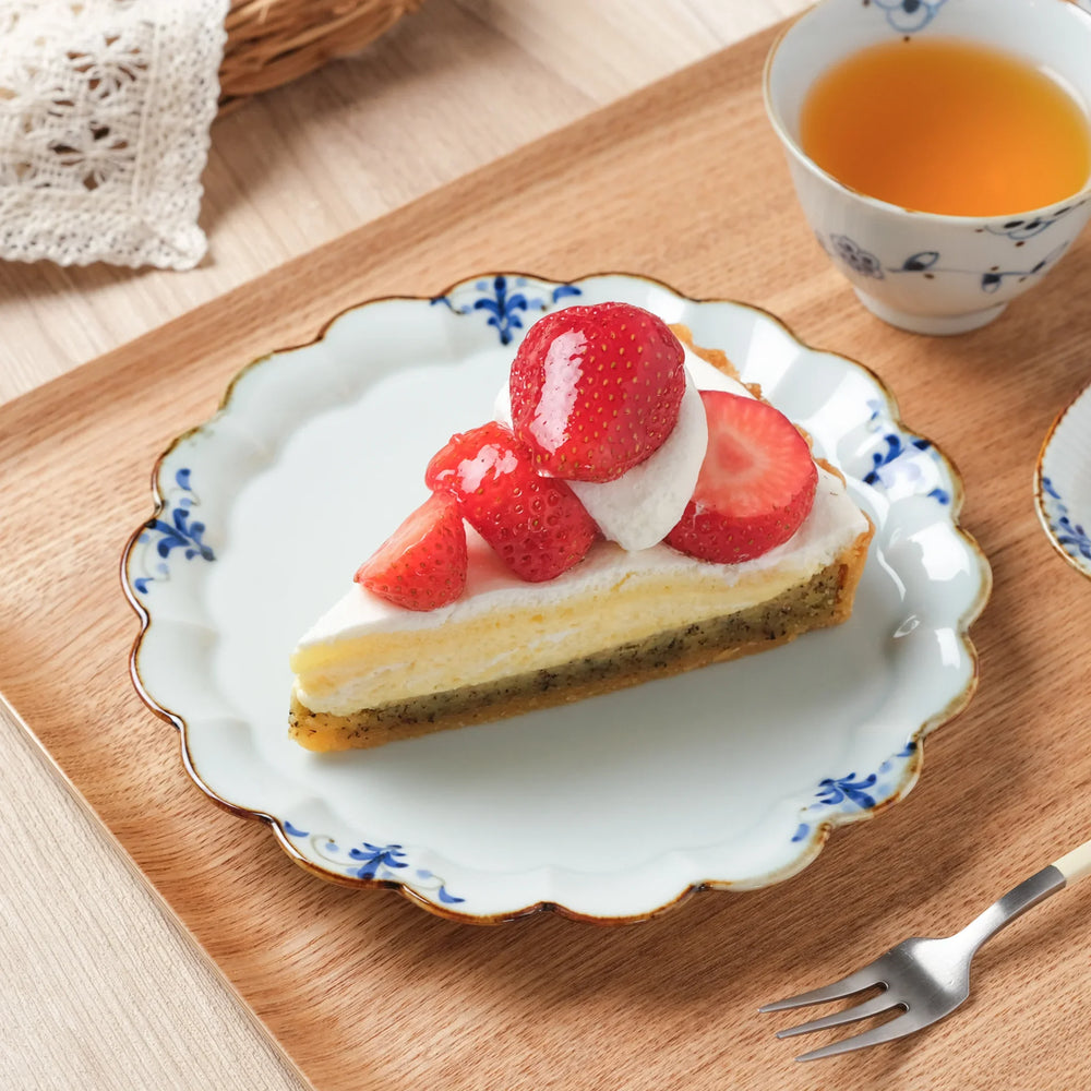 A Japanese porcelain dessert plate with scalloped edges and floral leaves design, served with strawberry shortcake.