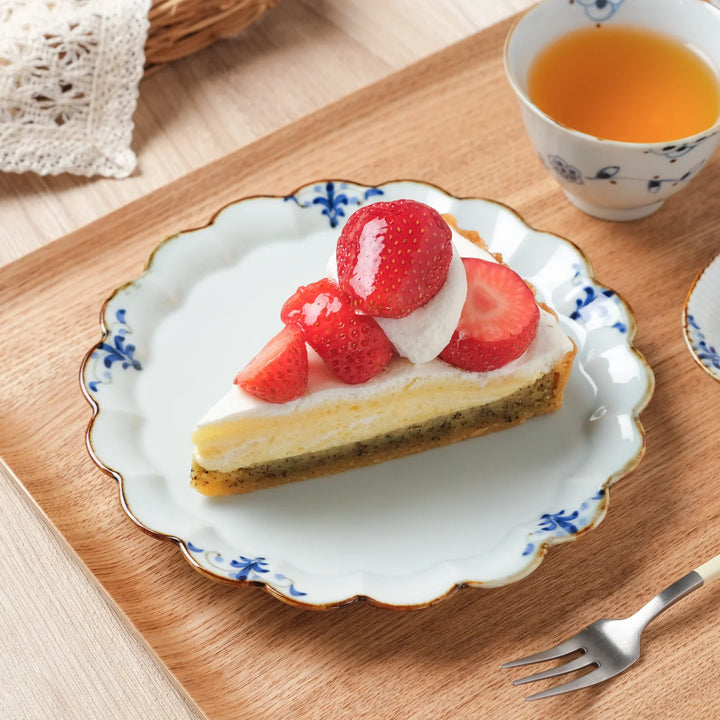 A Japanese porcelain dessert plate with scalloped edges and floral leaves design, served with strawberry shortcake.