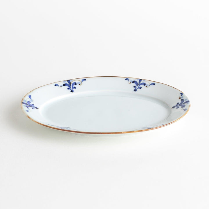 A porcelain oval salad plate, decorated with blue and white floral motifs and brown accent trim.