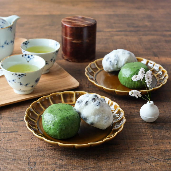 Amber flower-petal dessert plates holding traditional Japanese sweets, paired with floral teacups and a cherry bark tea caddy for a serene teatime.