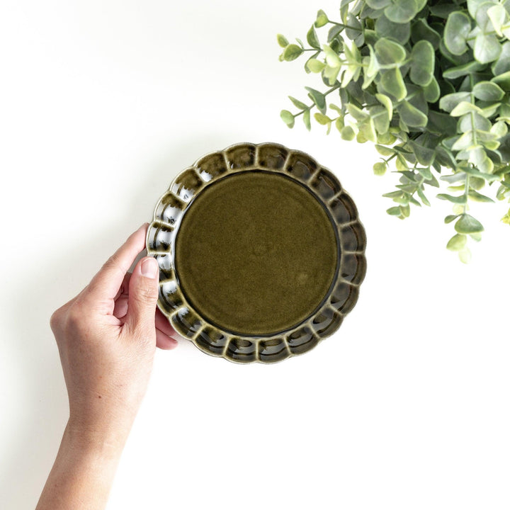Round, dark brown or olive colored dessert plate with a scalloped edge, featuring a glossy finish.