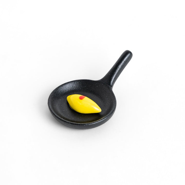 Cute frying pan-shaped chopstick rest with a yellow omelette accent, adding a fun touch to your dining experience.