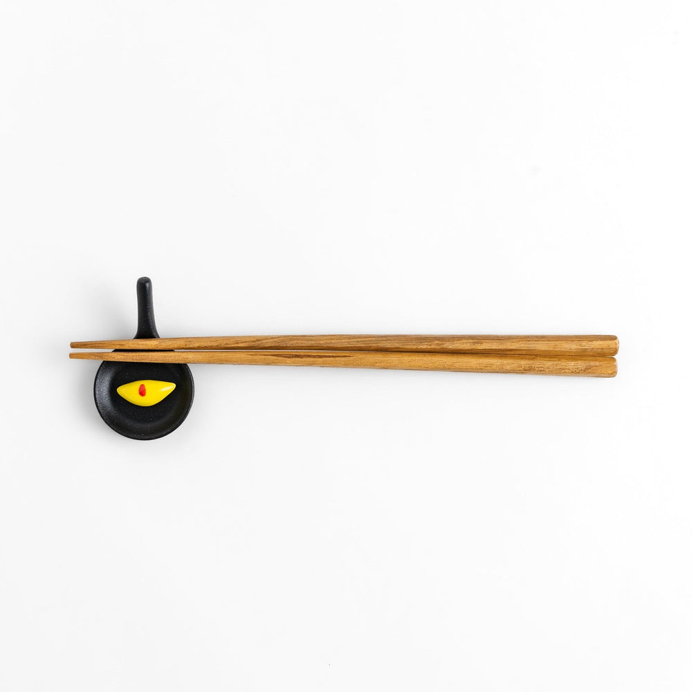 Cute frying pan-shaped chopstick rest with a yellow omelette accent, adding a fun touch to your dining experience.