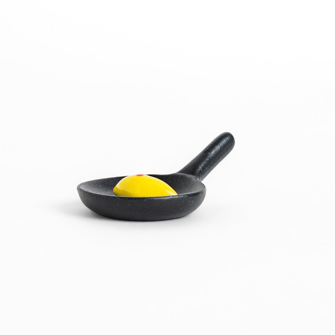 Cute frying pan-shaped chopstick rest with a yellow omelette accent, adding a fun touch to your dining experience.