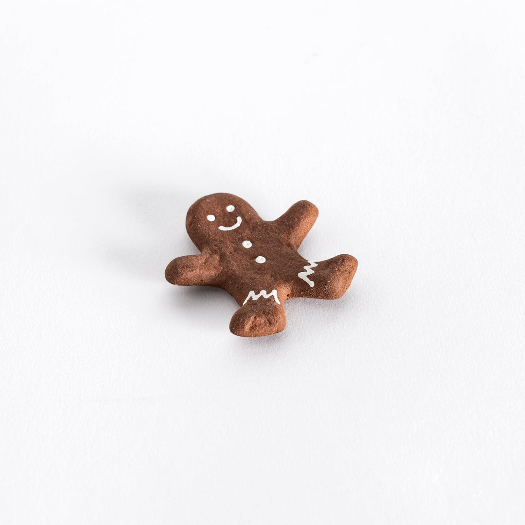 Slightly angled view of a gingerbread man-shaped chopstick rest with chopsticks placed on it, capturing the details of the shape and icing.