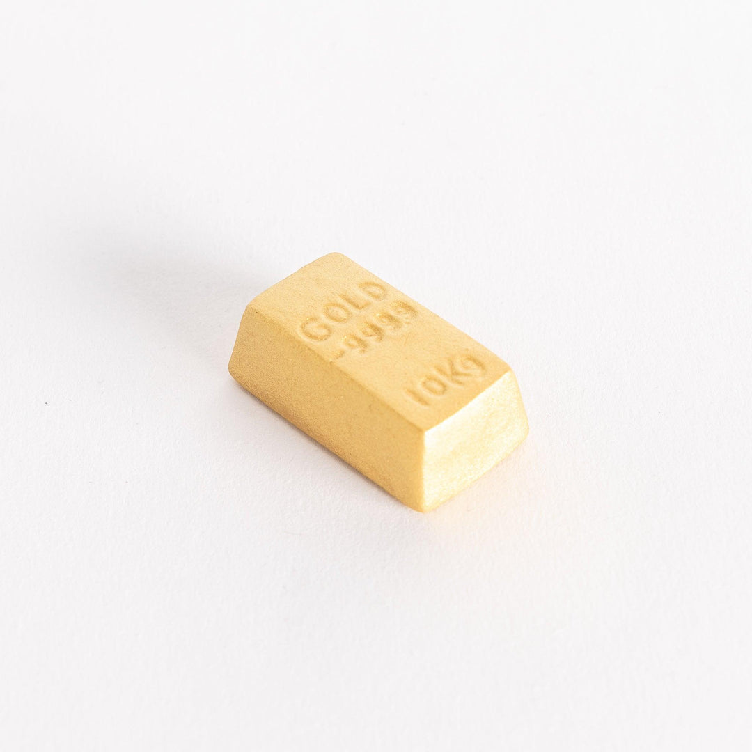 A gold bar-shaped ceramic chopstick rest with "GOLD 999.9" and "10KG" embossed on the top.