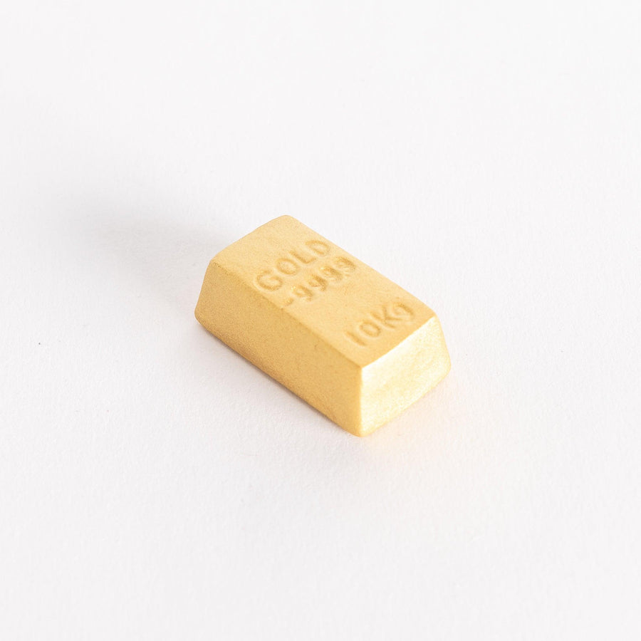 A gold bar-shaped ceramic chopstick rest with "GOLD 999.9" and "10KG" embossed on the top.