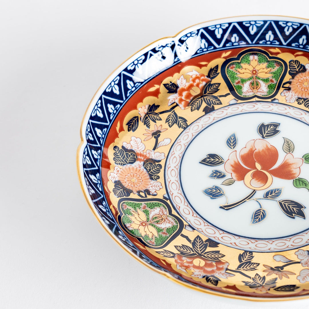 A floral salad plate with intricate gold detailing, showcasing a vibrant red flower at its center surrounded by intricate patterns in green, blue, and gold.