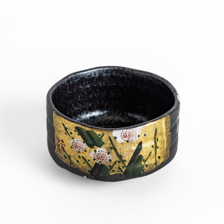 Matcha Bowl featuring a beautiful gold leaf and plum blossom design, set against a dark, textured background.