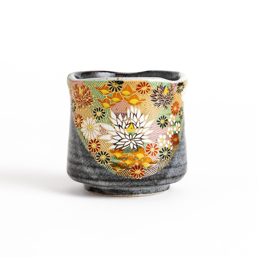 Gray ceramic teacup with a vibrant floral pattern in gold and pastel colors, featuring a unique speckled glaze and a slightly flared rim.