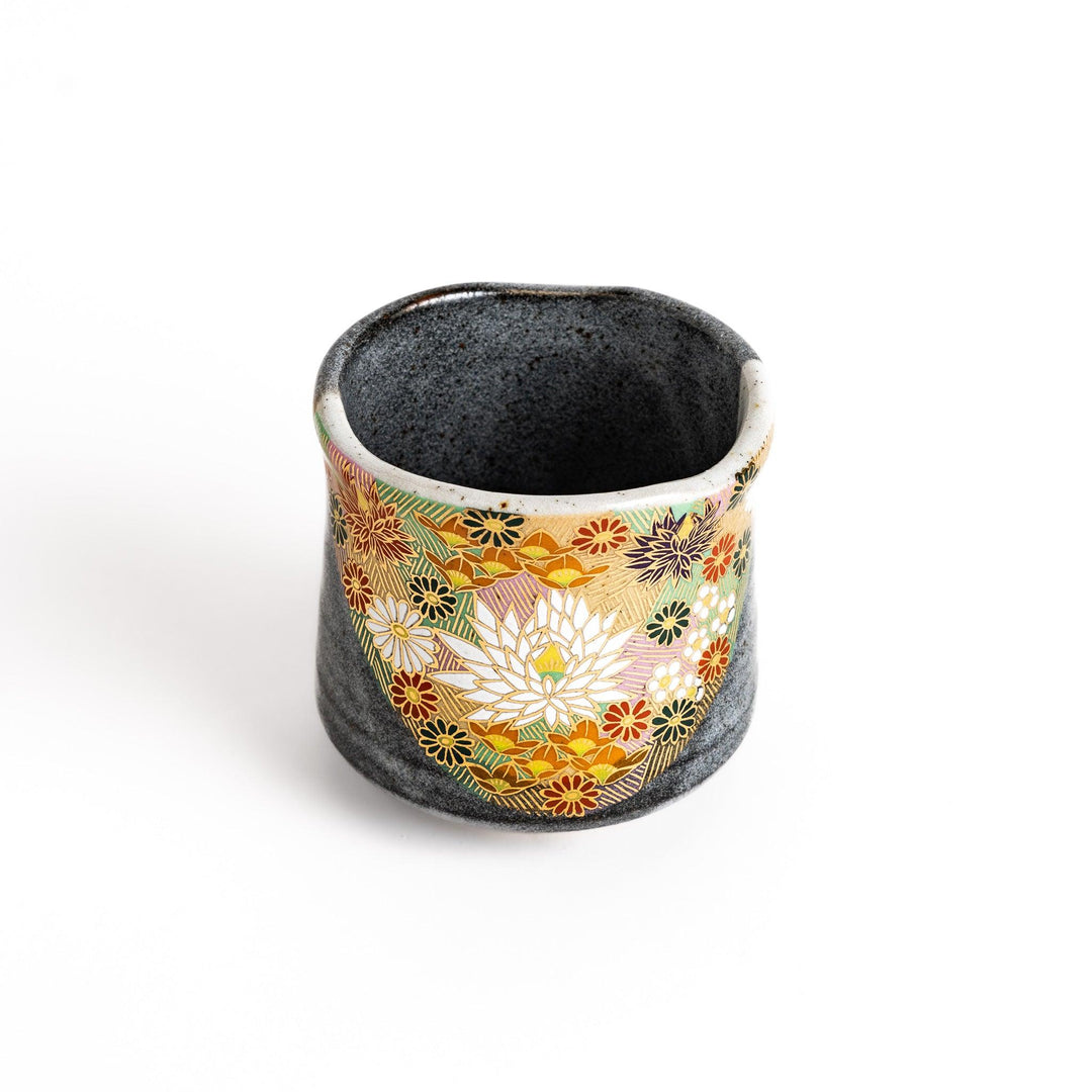 Gray ceramic teacup with a vibrant floral pattern in gold and pastel colors, featuring a unique speckled glaze and a slightly flared rim.