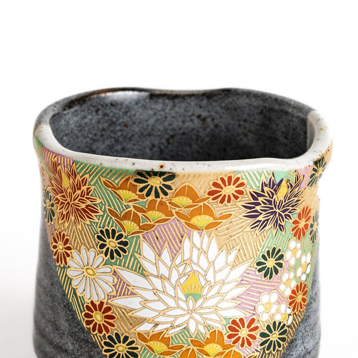 Gray ceramic teacup with a vibrant floral pattern in gold and pastel colors, featuring a unique speckled glaze and a slightly flared rim.