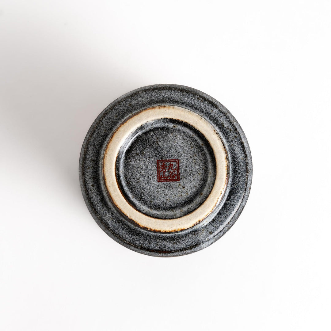 Gray ceramic teacup with a vibrant floral pattern in gold and pastel colors, featuring a unique speckled glaze and a slightly flared rim.