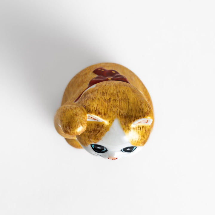 Maneki Neko figurine with a golden brush design, featuring a waving cat with a collar and bell for good luck.