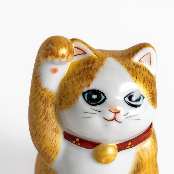 Maneki Neko figurine with a golden brush design, featuring a waving cat with a collar and bell for good luck.