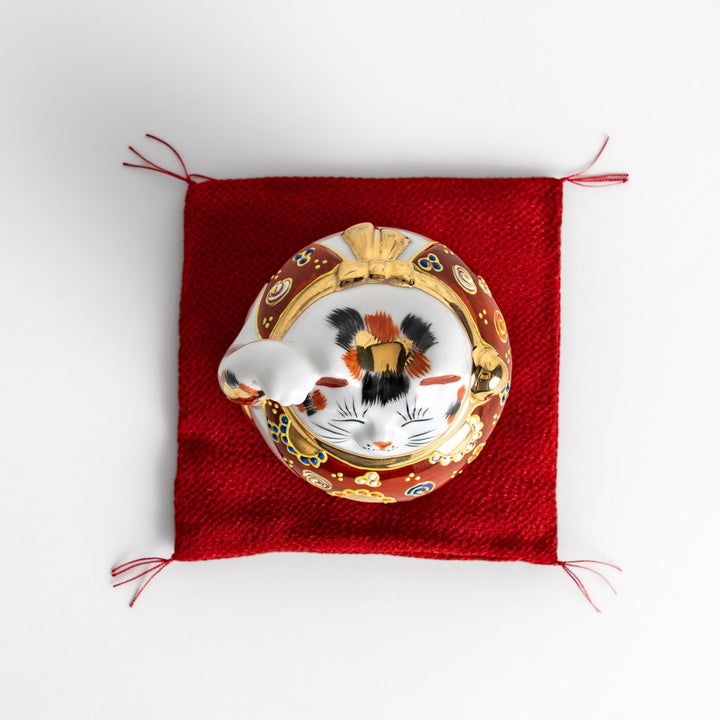 Maneki Neko figurine featuring a golden calico design, a raised paw, and a red patterned collar for good fortune.