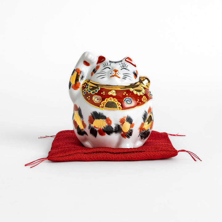 Maneki Neko figurine featuring a golden calico design, a raised paw, and a red patterned collar for good fortune.